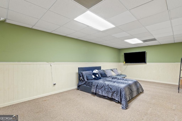 carpeted bedroom featuring a wainscoted wall and a paneled ceiling