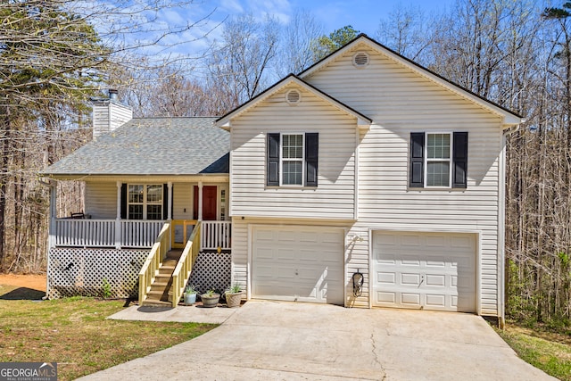 tri-level home with covered porch, concrete driveway, roof with shingles, a chimney, and an attached garage