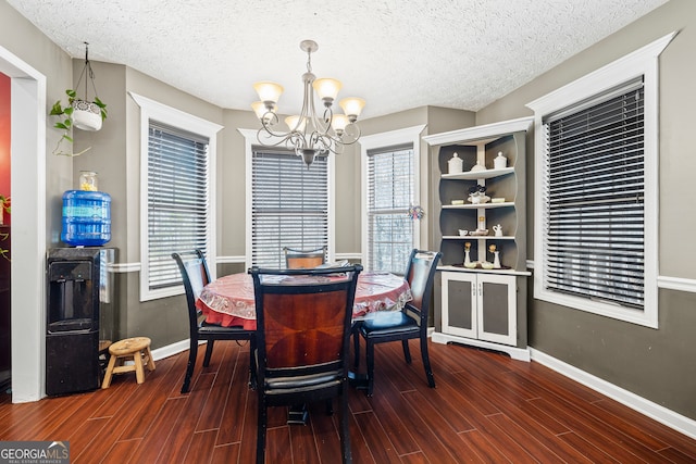 dining area with a textured ceiling, baseboards, a chandelier, and wood finished floors