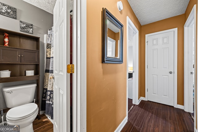 corridor featuring baseboards, a textured ceiling, and dark wood finished floors