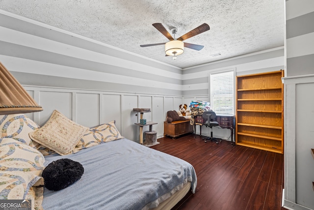 bedroom featuring a textured ceiling, a wainscoted wall, visible vents, ceiling fan, and wood finished floors