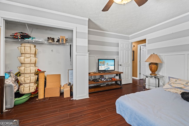 bedroom with a ceiling fan, wood finished floors, a decorative wall, and a textured ceiling