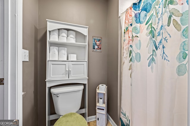 bathroom with baseboards, a shower with shower curtain, and toilet