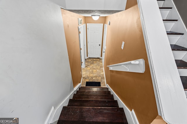 stairs featuring baseboards and stone finish flooring