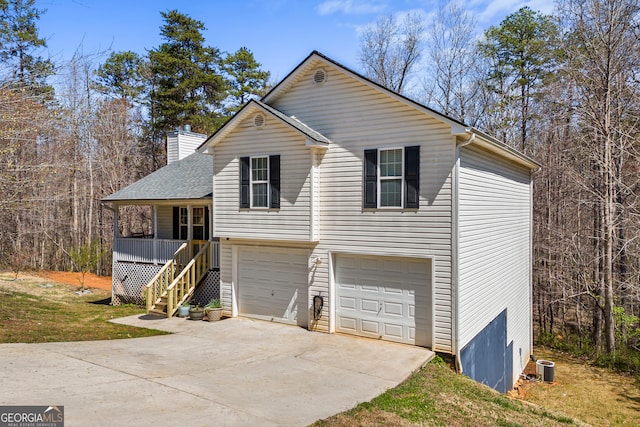 view of front of house with covered porch, stairway, concrete driveway, a chimney, and a garage