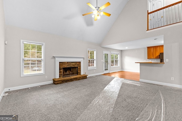 unfurnished living room featuring carpet flooring, high vaulted ceiling, baseboards, a fireplace, and ceiling fan