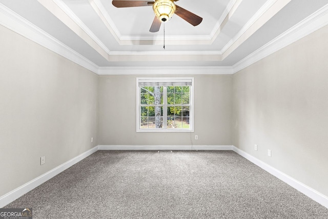 carpeted spare room with baseboards, a tray ceiling, a ceiling fan, and ornamental molding