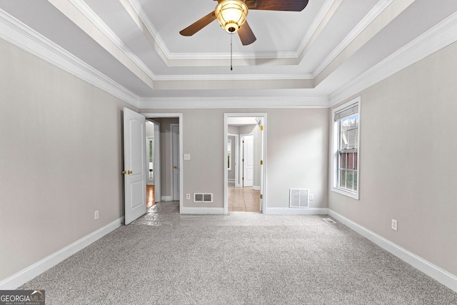 interior space with carpet flooring, a tray ceiling, baseboards, and visible vents