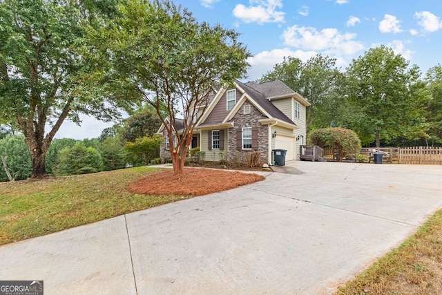 view of front facade with driveway, a front yard, stone siding, fence, and an attached garage