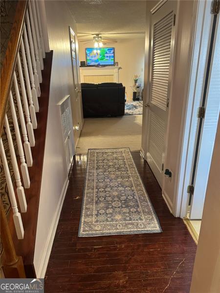 corridor featuring baseboards, stairs, and wood finished floors