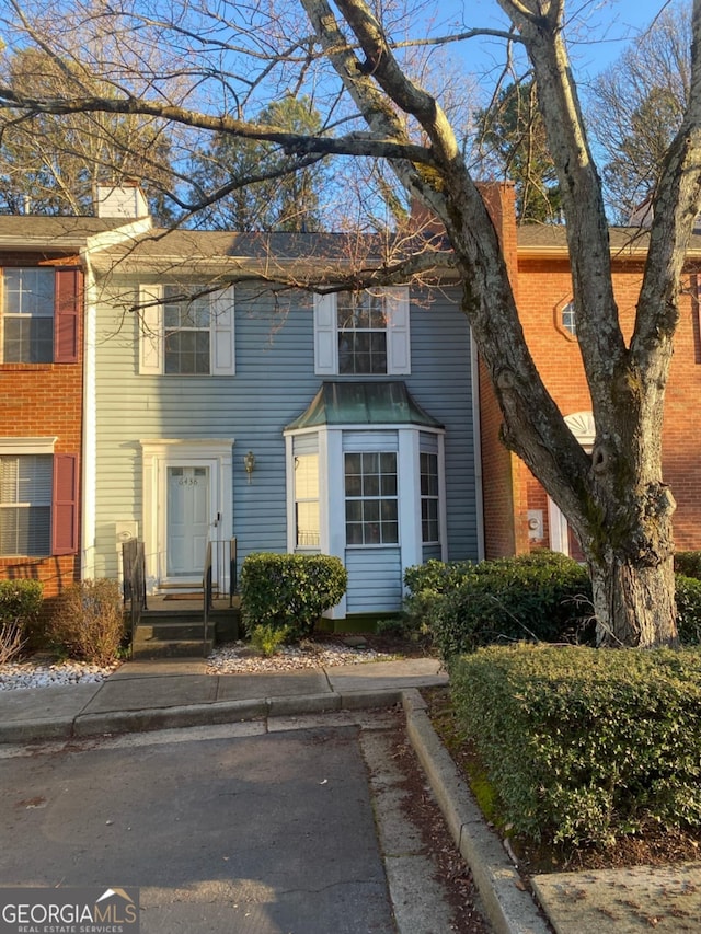 view of front of property with a chimney and brick siding