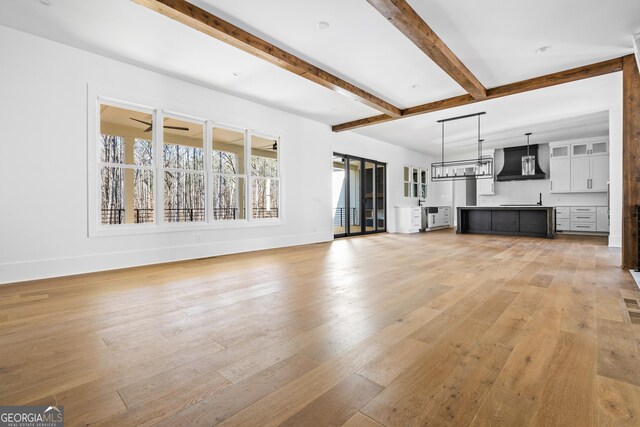 18390 Birmingham Hwy, Alpharetta, GA 30004 - unfurnished living room with baseboards, light wood-type flooring, beam ceiling, and a ceiling fan