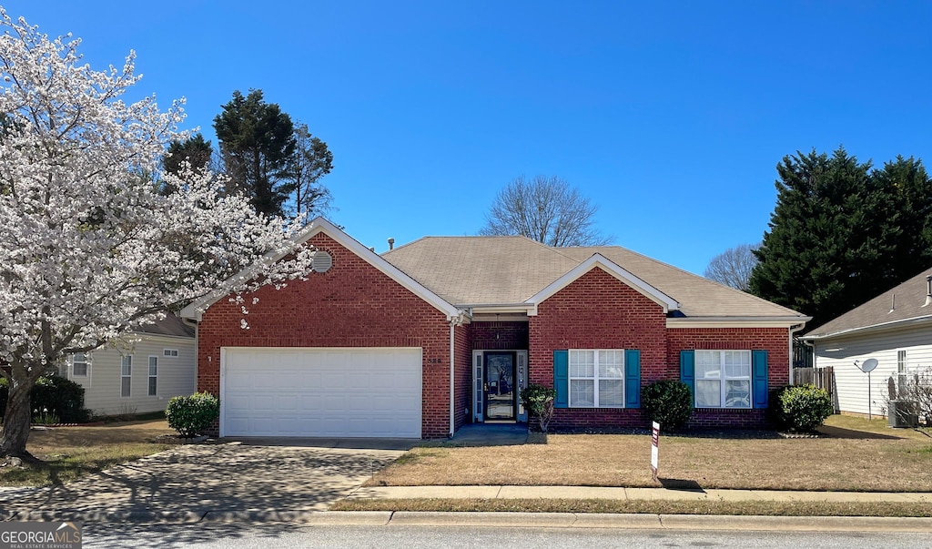 ranch-style home with a front lawn, an attached garage, brick siding, and concrete driveway