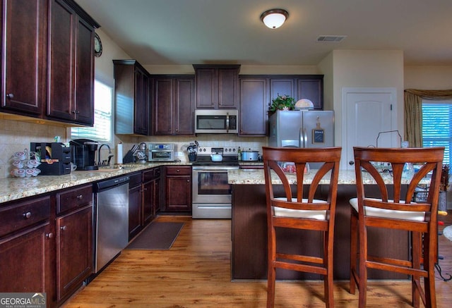 kitchen featuring stainless steel appliances, visible vents, decorative backsplash, and a sink