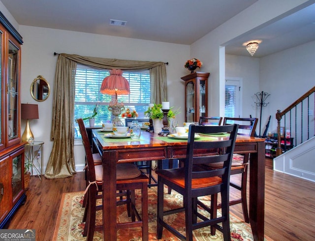 dining room with stairs, wood finished floors, and visible vents