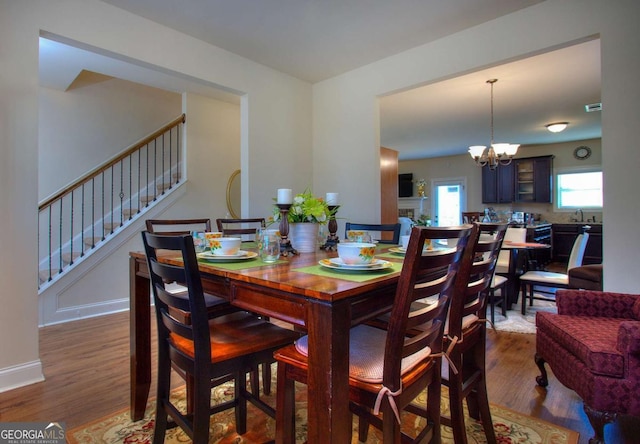 dining space featuring baseboards, stairs, wood finished floors, and a notable chandelier