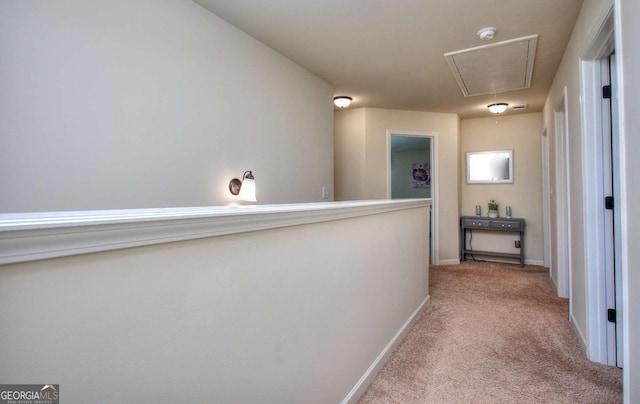 hallway featuring carpet floors, attic access, and baseboards