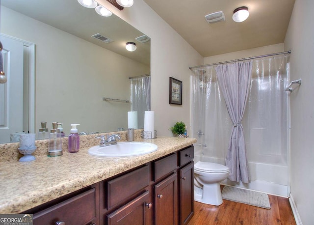 bathroom featuring visible vents, wood finished floors, vanity, toilet, and shower / tub combo with curtain