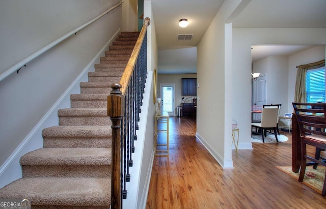stairway featuring baseboards, wood finished floors, and visible vents