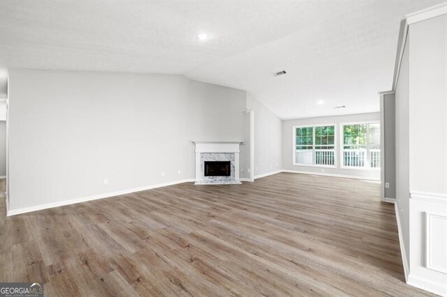 1590 Highland Farm Dr, Suwanee, GA 30024 - unfurnished living room featuring wood finished floors, lofted ceiling, a premium fireplace, baseboards, and recessed lighting