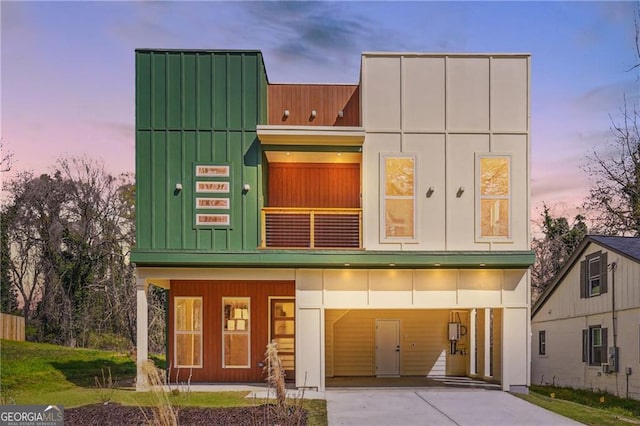 modern home featuring driveway, a balcony, and a carport