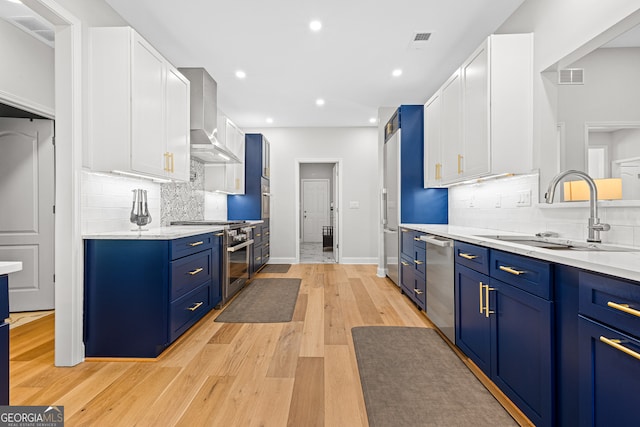 2105 Rotunda Ct, Conyers, GA 30094 - kitchen featuring blue cabinetry, stainless steel appliances, white cabinetry, a sink, and wall chimney range hood
