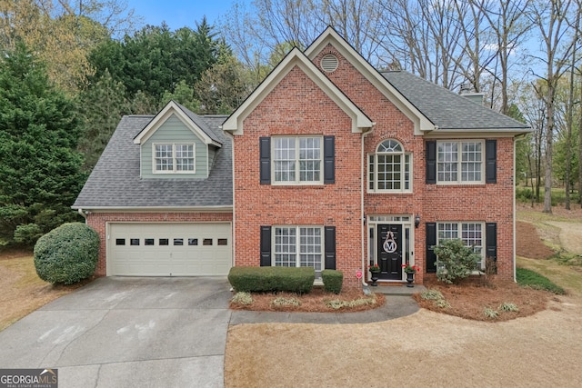 colonial home with brick siding, a shingled roof, an attached garage, and driveway