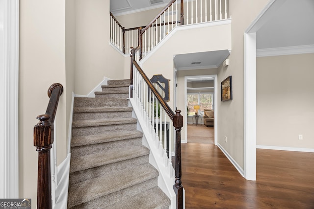 stairs featuring crown molding, baseboards, wood finished floors, and visible vents
