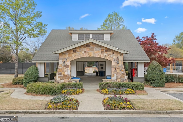 view of front of home with fence, a shingled roof, and stone siding