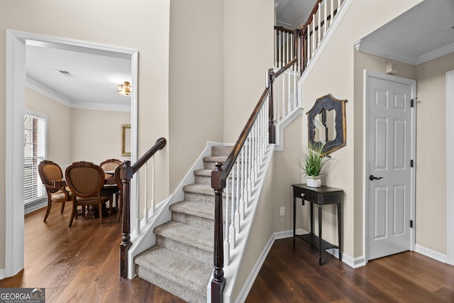 stairway with crown molding, baseboards, visible vents, and wood finished floors
