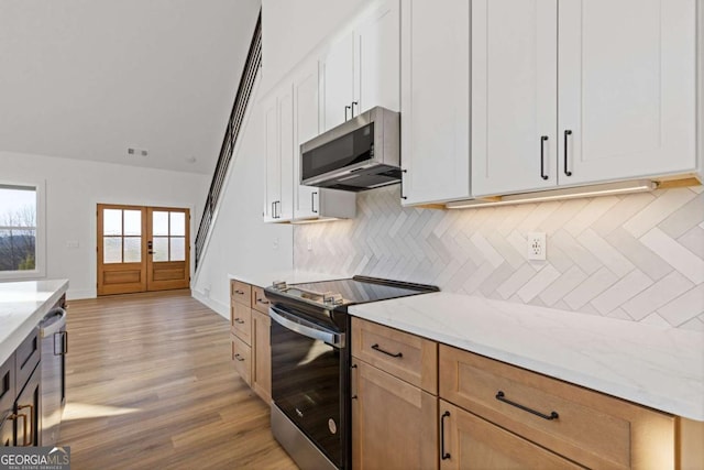 kitchen with light stone countertops, appliances with stainless steel finishes, visible vents, light wood-style floors, and decorative backsplash