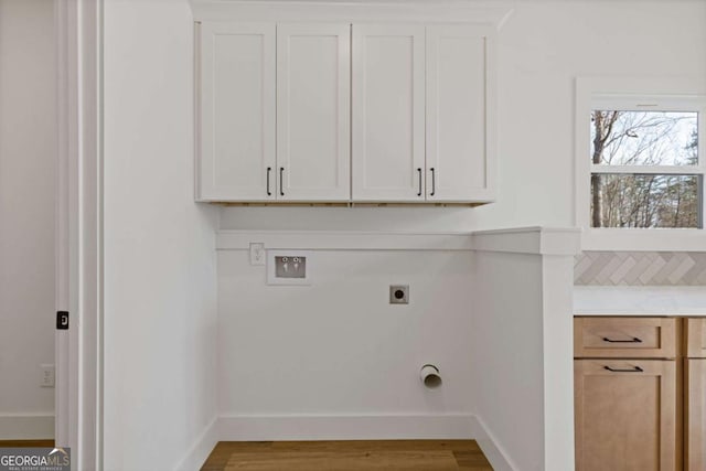 clothes washing area featuring hookup for an electric dryer, washer hookup, baseboards, cabinet space, and wood finished floors