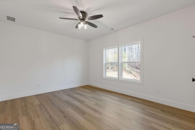 empty room with baseboards, visible vents, wood finished floors, and ceiling fan