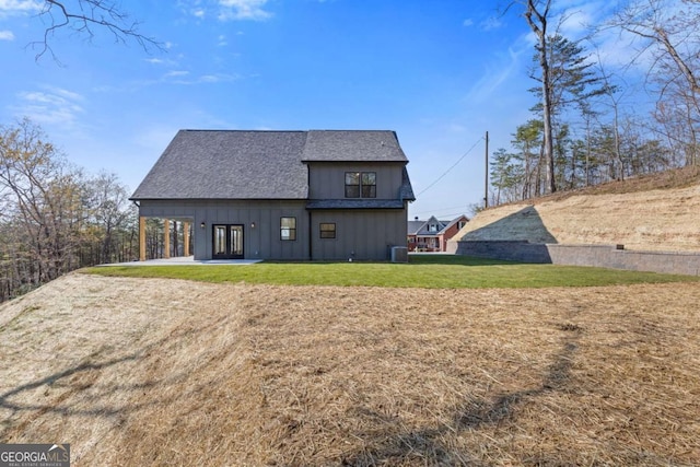 back of property featuring board and batten siding, central AC, a yard, and a shingled roof