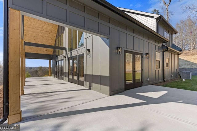 exterior space with french doors, board and batten siding, cooling unit, and a patio area