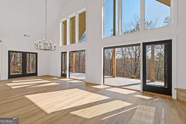 interior space with french doors, a chandelier, wood finished floors, baseboards, and visible vents