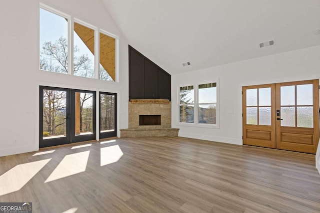 unfurnished living room featuring french doors, high vaulted ceiling, a healthy amount of sunlight, and visible vents