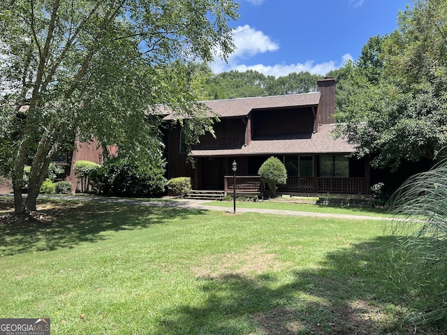 view of front of home with a porch, a front yard, roof with shingles, and a chimney