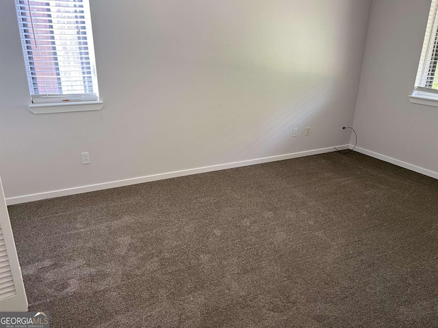 empty room with baseboards and dark colored carpet
