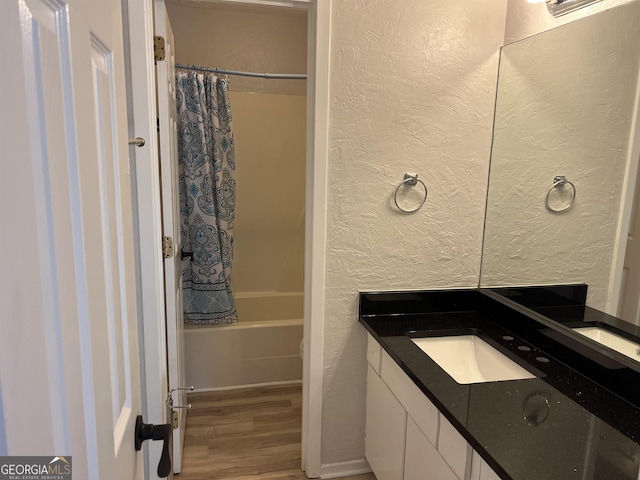full bathroom featuring shower / bathtub combination with curtain, a textured wall, vanity, and wood finished floors