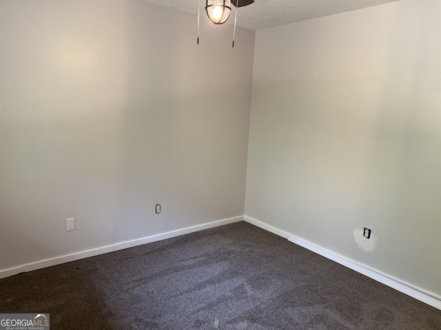 spare room featuring baseboards, dark colored carpet, ceiling fan, and a textured ceiling
