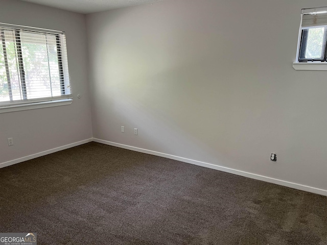 spare room featuring baseboards and dark colored carpet