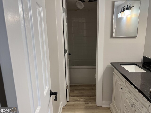 bathroom with baseboards, bathtub / shower combination, wood finished floors, and vanity