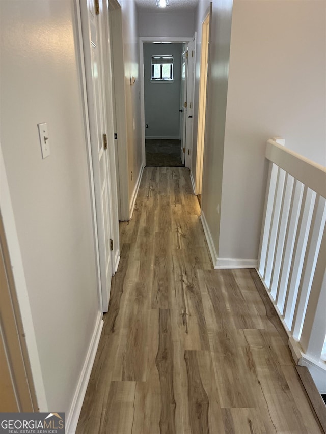 corridor featuring baseboards and wood finished floors