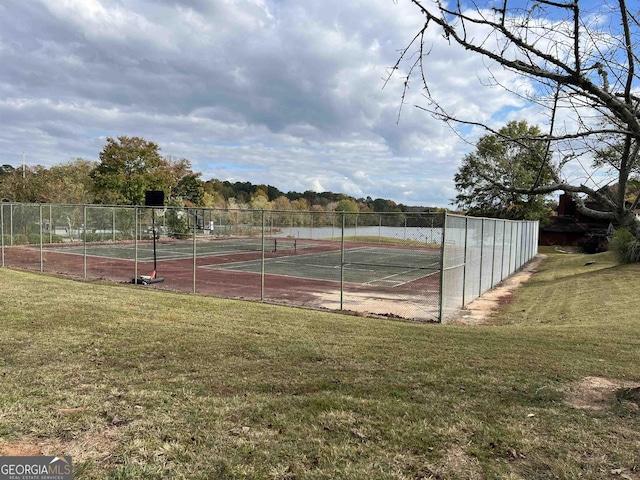 view of tennis court featuring fence and a yard
