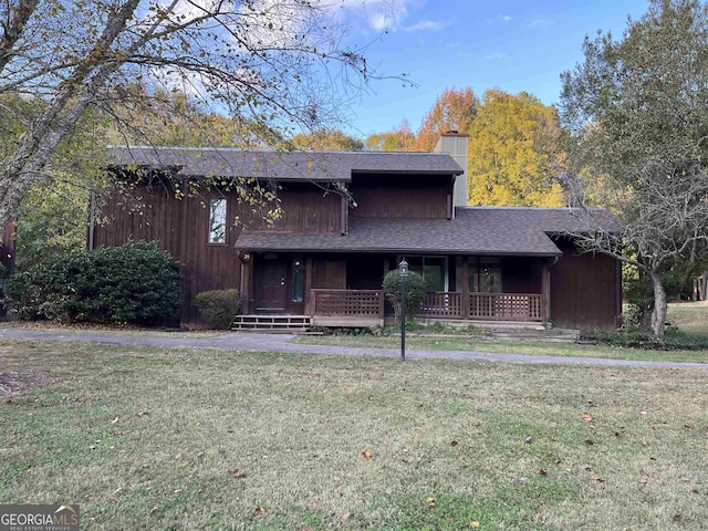view of front of house with a chimney, a porch, a shingled roof, and a front lawn