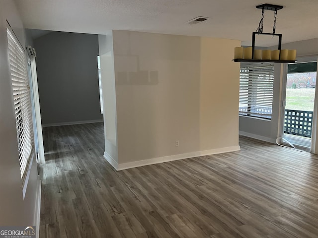 unfurnished dining area with baseboards, a textured ceiling, visible vents, and wood finished floors