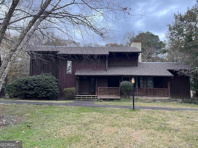 view of front of home with a chimney, a front yard, a porch, and roof with shingles