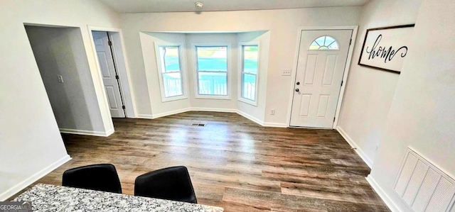 foyer with wood finished floors, baseboards, and visible vents