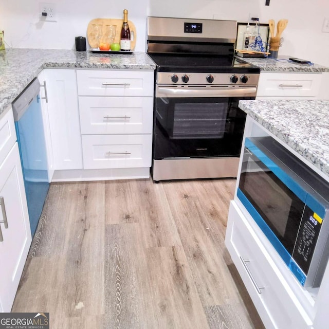 kitchen with light wood finished floors, white cabinetry, light stone counters, and appliances with stainless steel finishes
